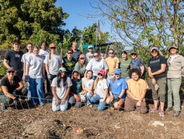 A group of youth and adult volunteers smiling together in a garden