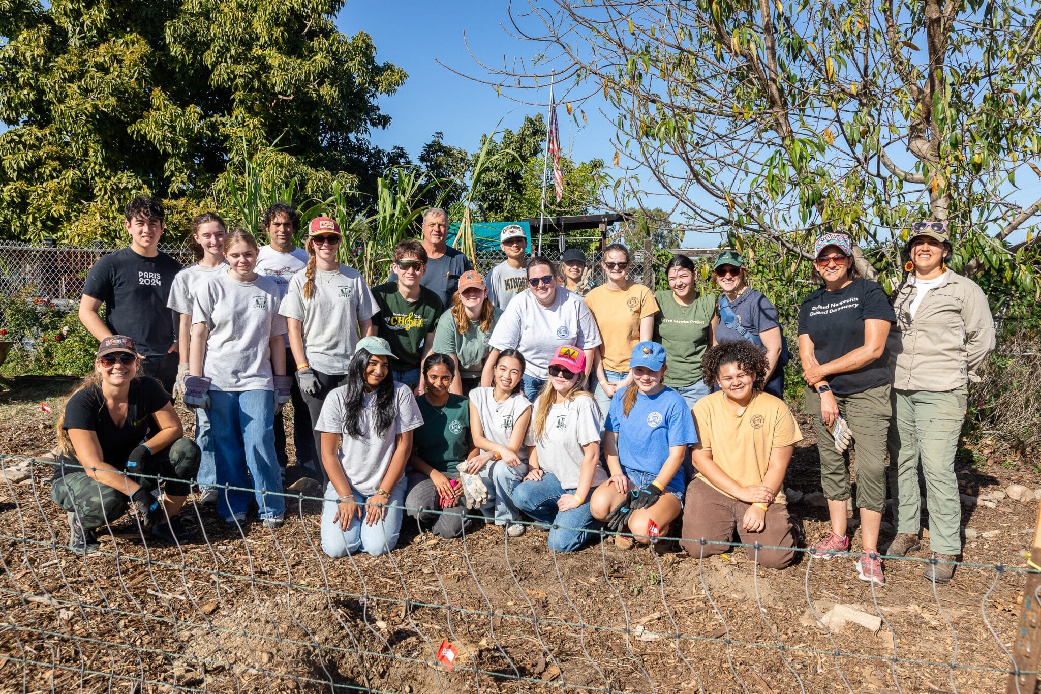A group of youth and adult volunteers smiling together in a garden